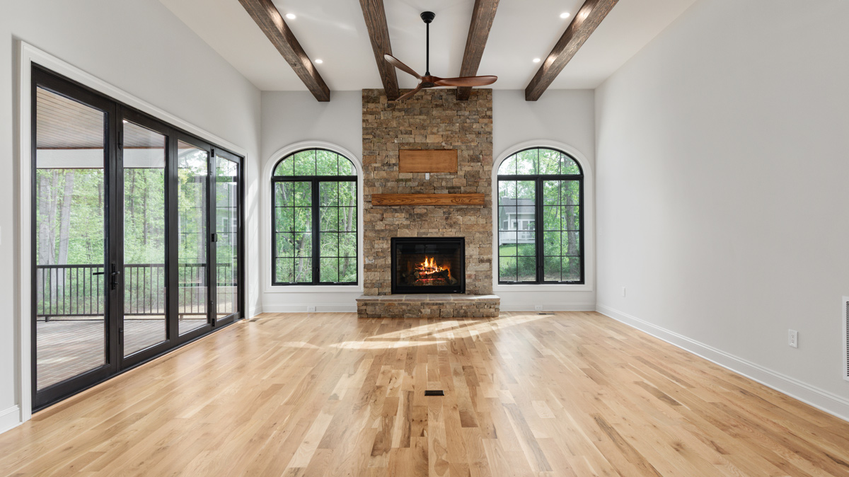 Living room with high ceilings, fireplace, and glass doors leading out to the patio