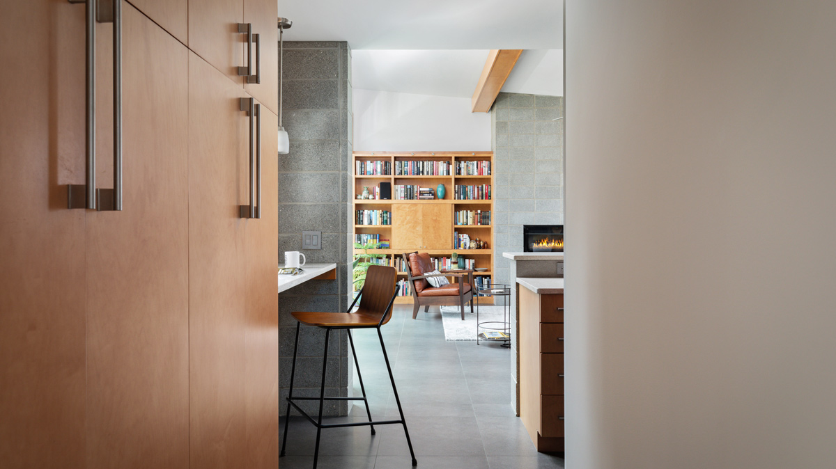 hallway view of kitchen and living room area with built in book shelf and fireplace