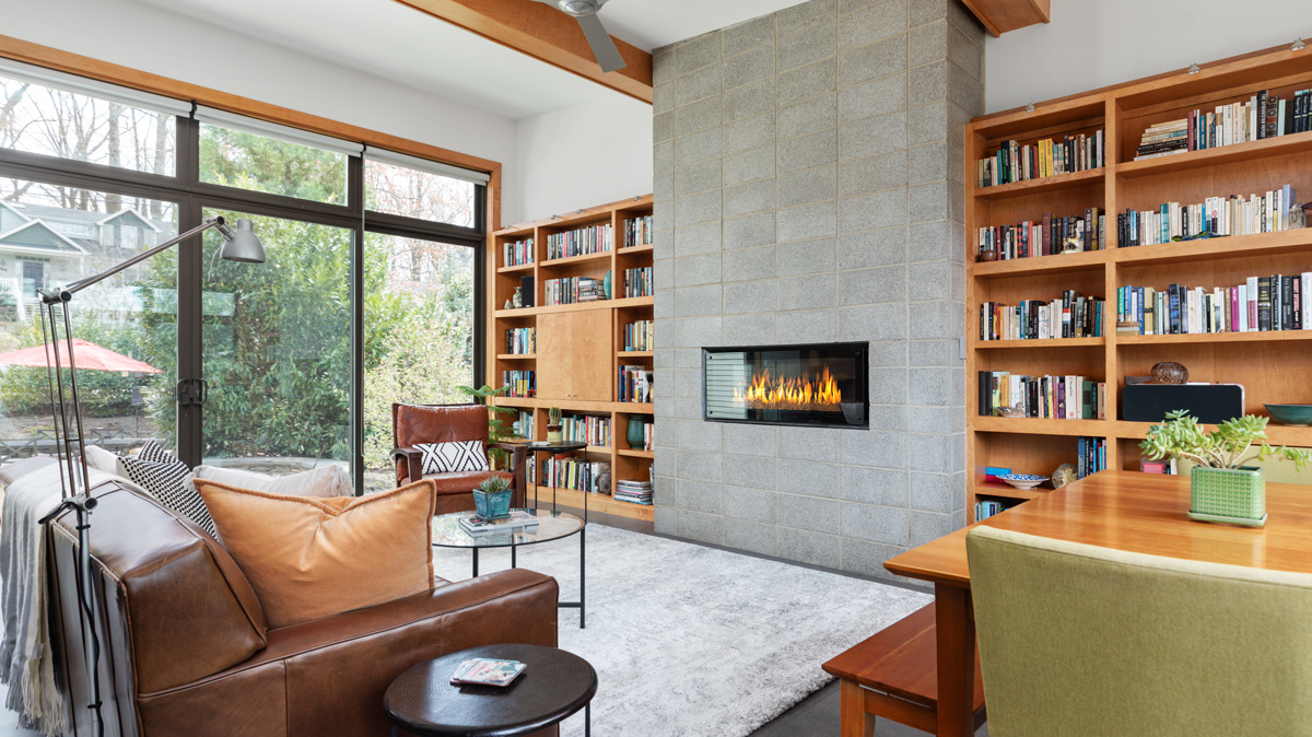 living room with built in bookshelves on either side of a cement block electric fireplace
