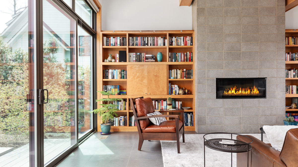 living room area with built in bookshelves and cement block electric fire place leading to the glass door out to the back deck