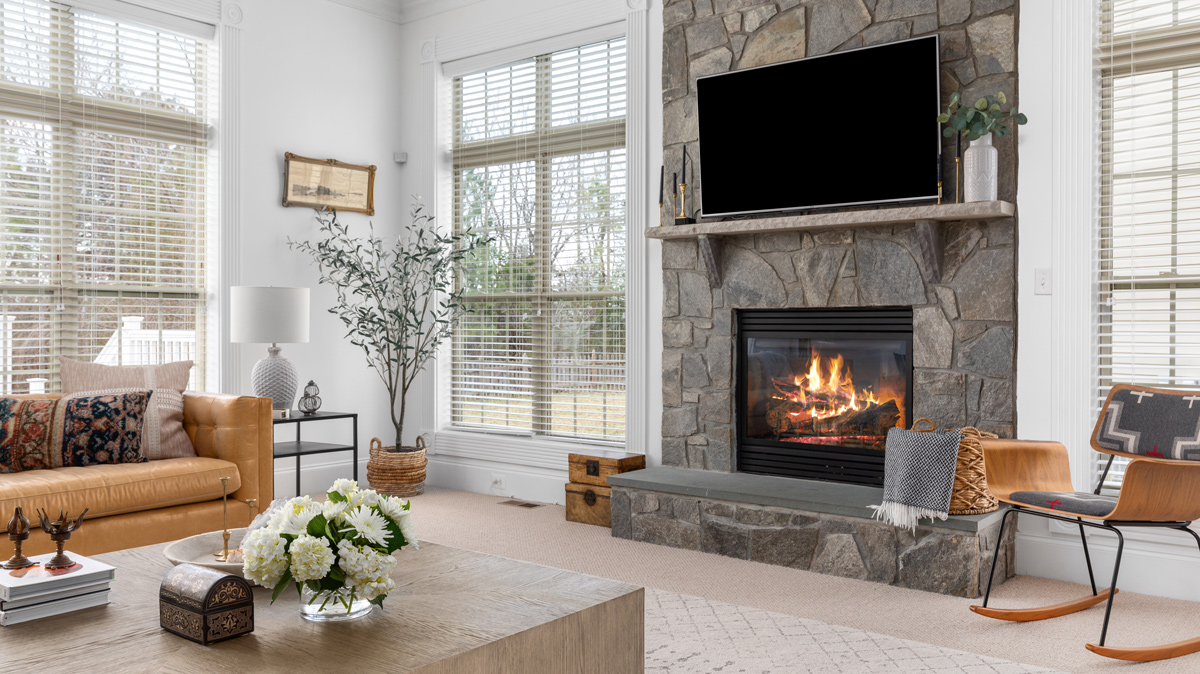 living room with cathedral ceilings, stone fireplace with mounted tv and large windows