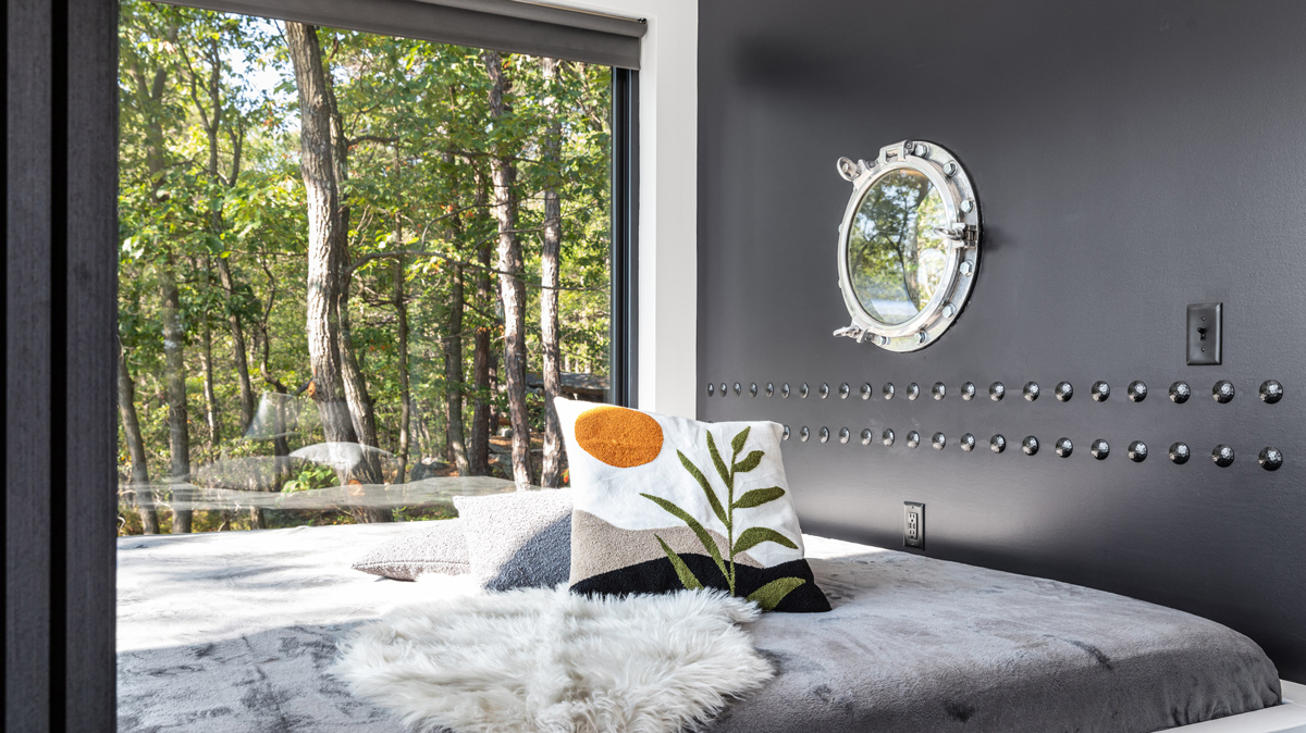bedroom with black wall designed like the side of a ship complete with a porthole