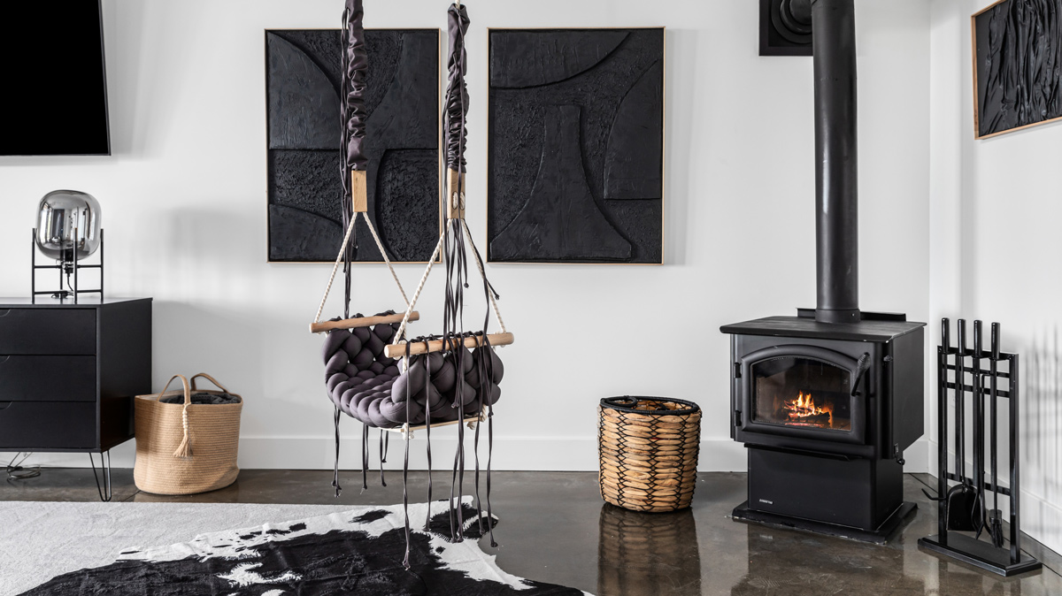 rustic living room with black and white accents featuring a swinging chair and wood stove