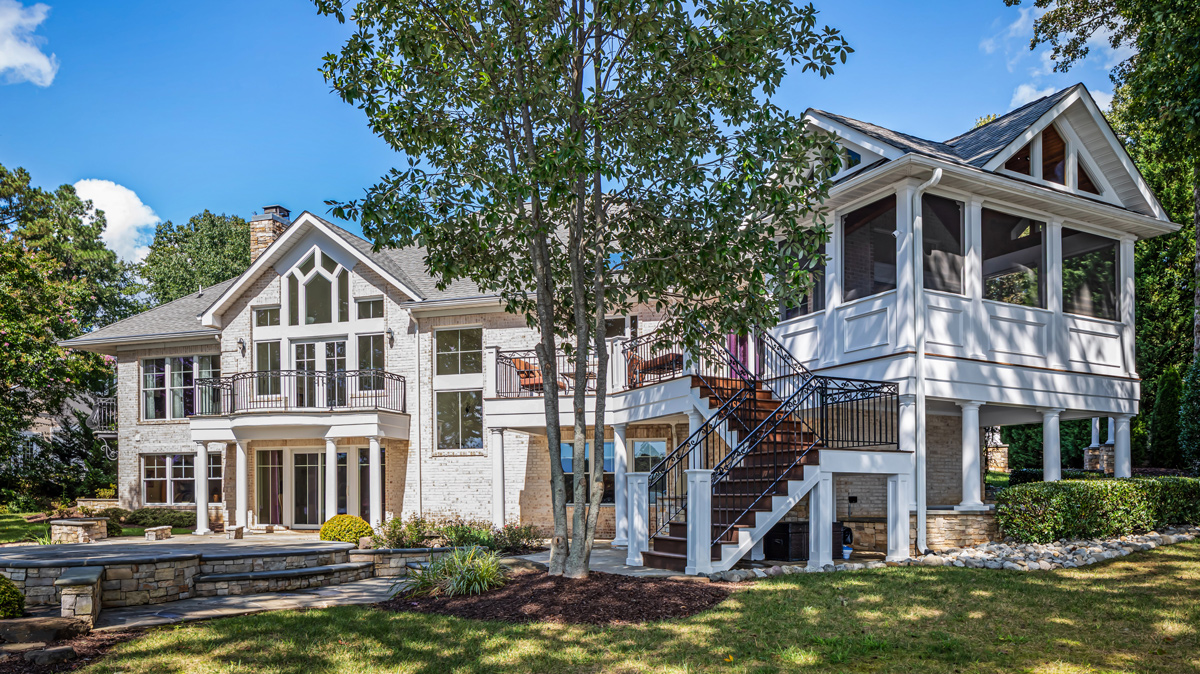 backyard landscaping of two story home with patio and multiple seating areas