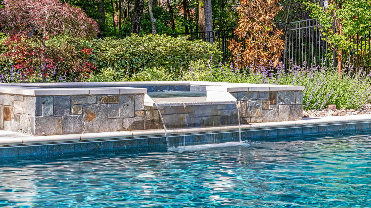 in-ground hot tub waterfall feeding into the in-ground pool