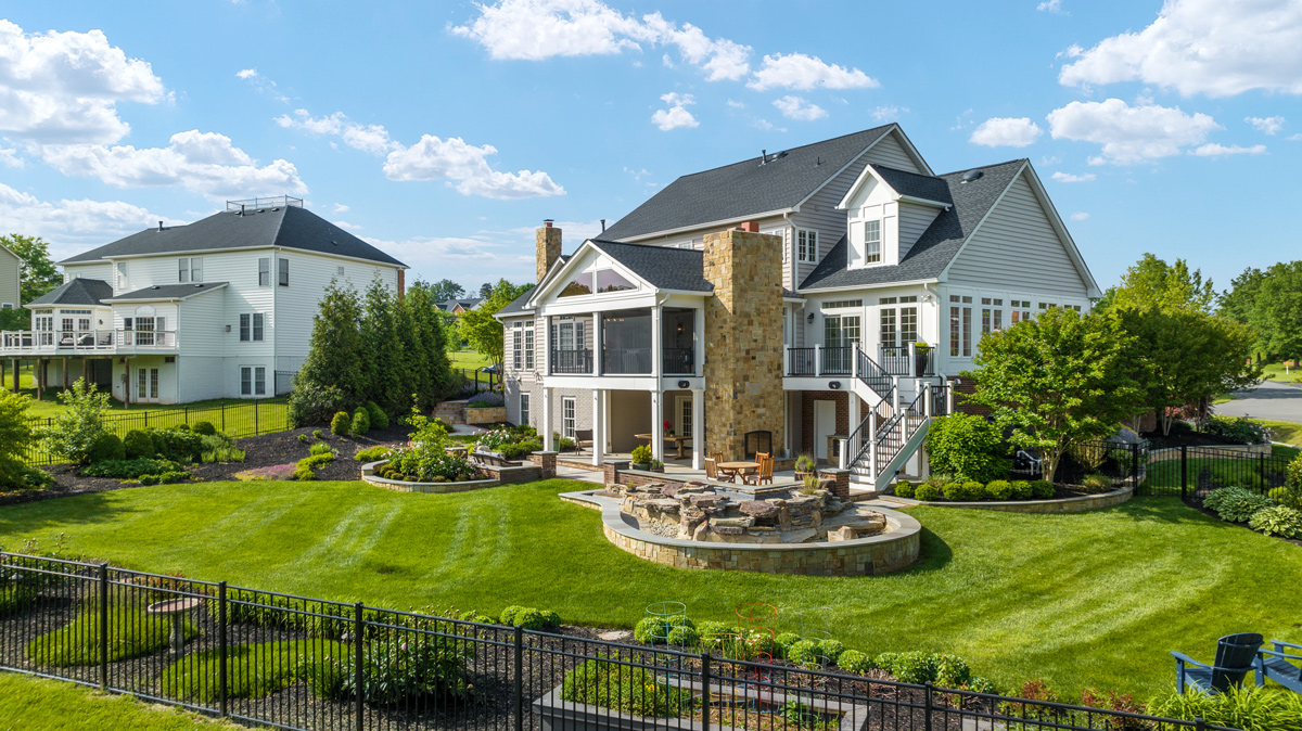 backyard view of a 2 story home with landscaping and seating areas