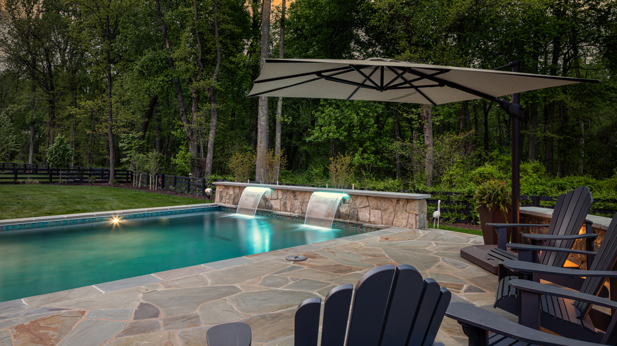 in-ground pool and patio lit up at dusk