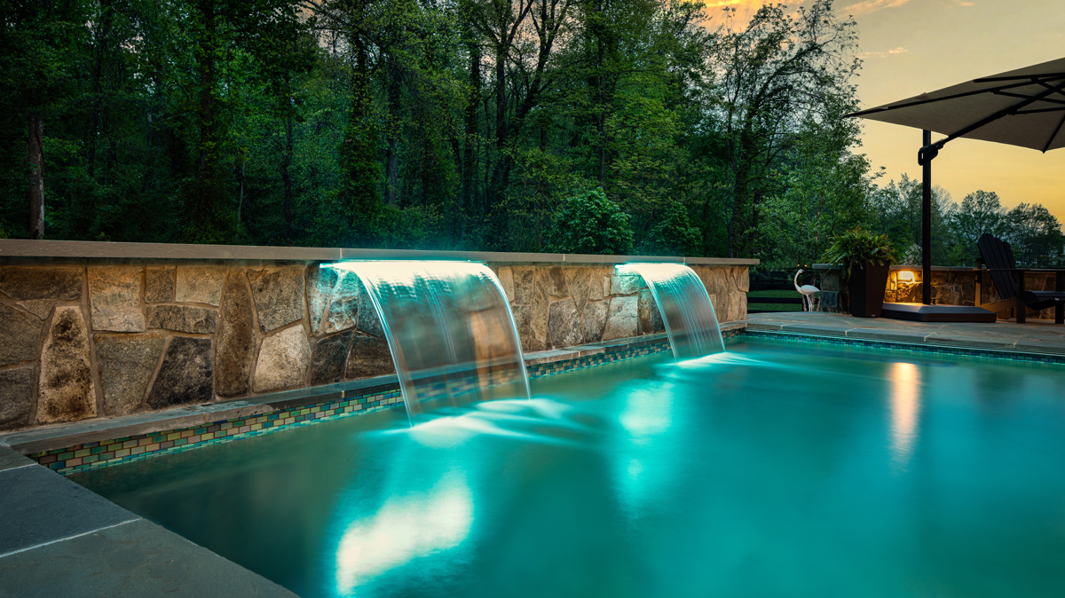two waterfall treatments lit up flowing into an in-ground pool