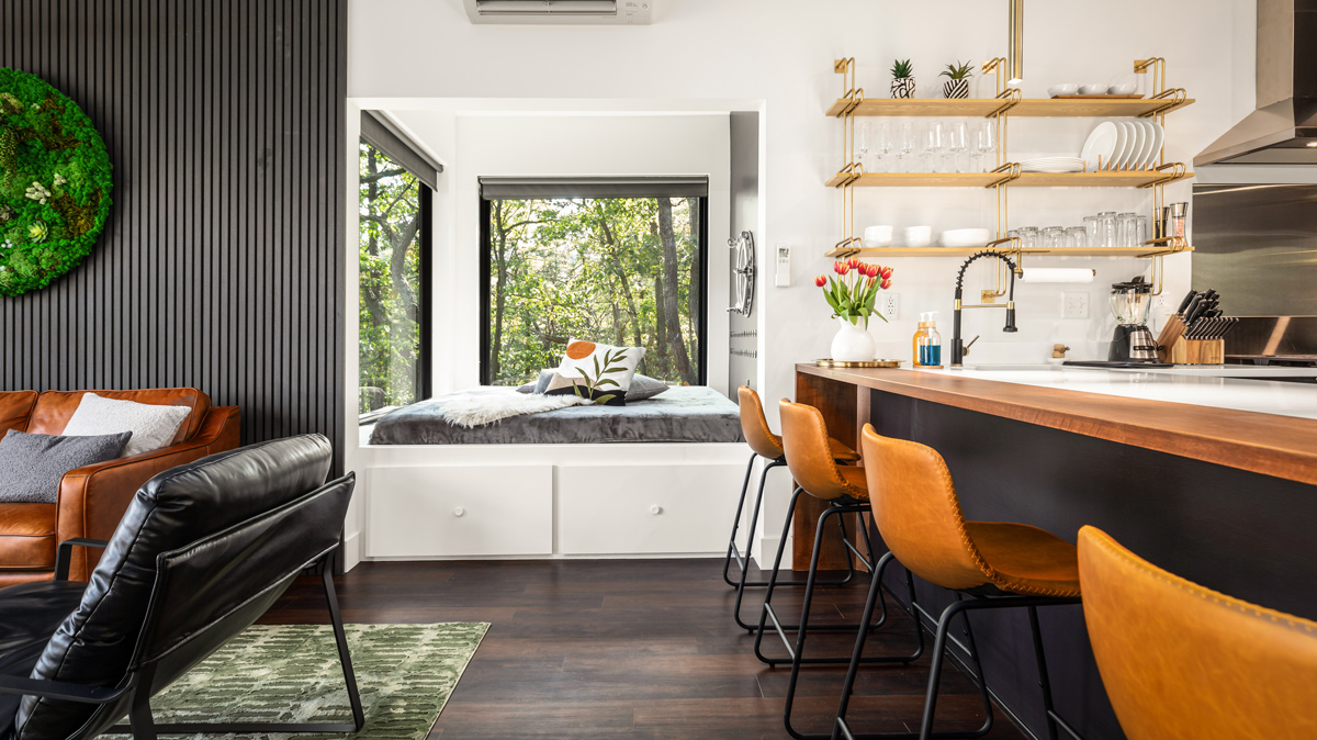 studio apartment featuring the kitchen with open shelving, bedroom with 180 degree views of the outdoors, and leather furnishings in the living room