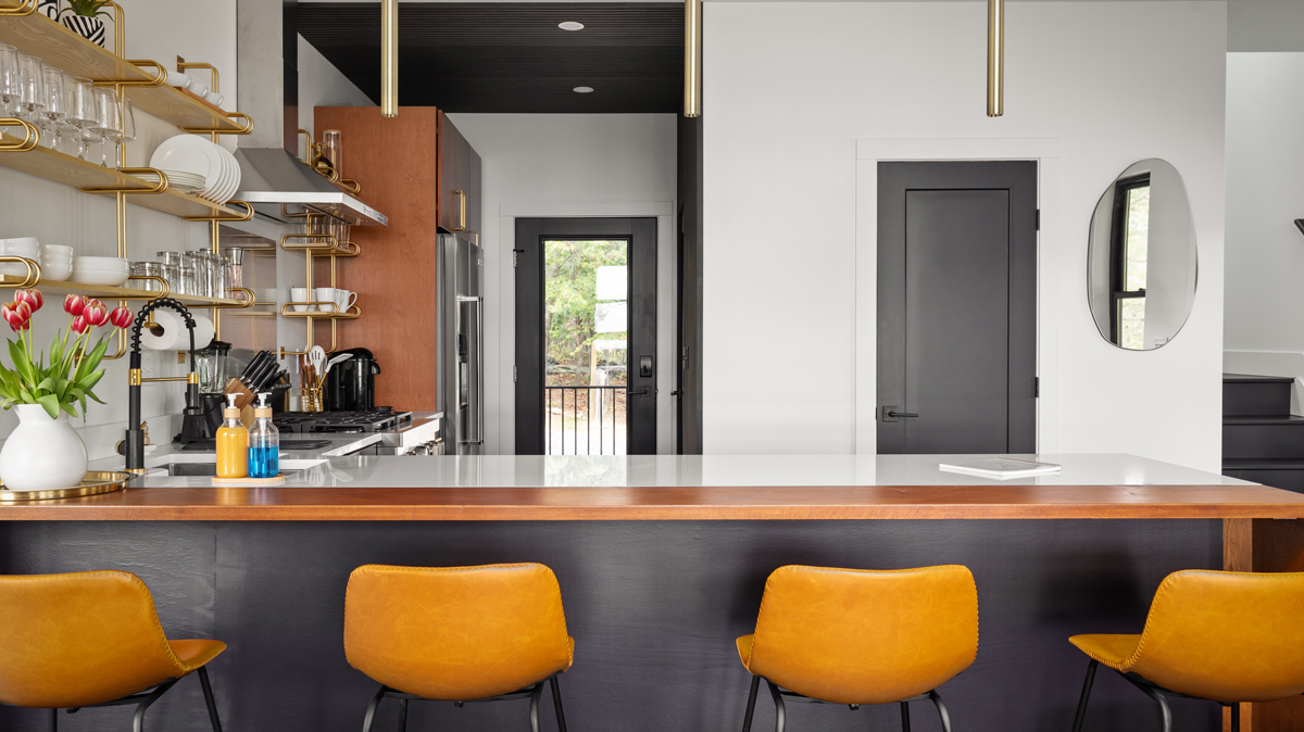 small kitchen with open shelving and island seating area with yellow leather stools