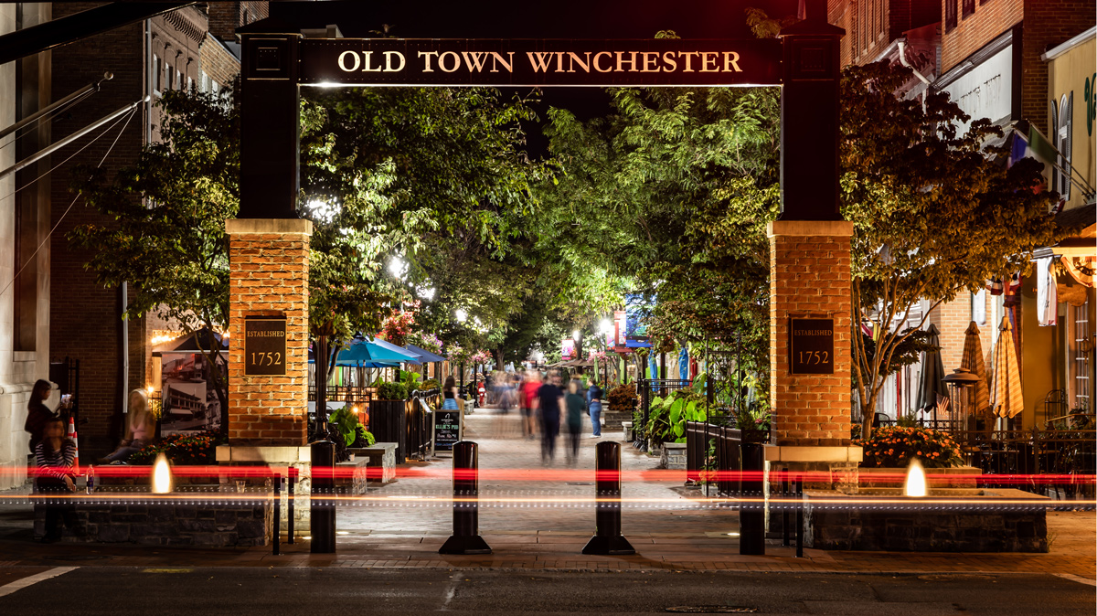 Old Town Winchester entrance with people walking down the walkway lit up at night